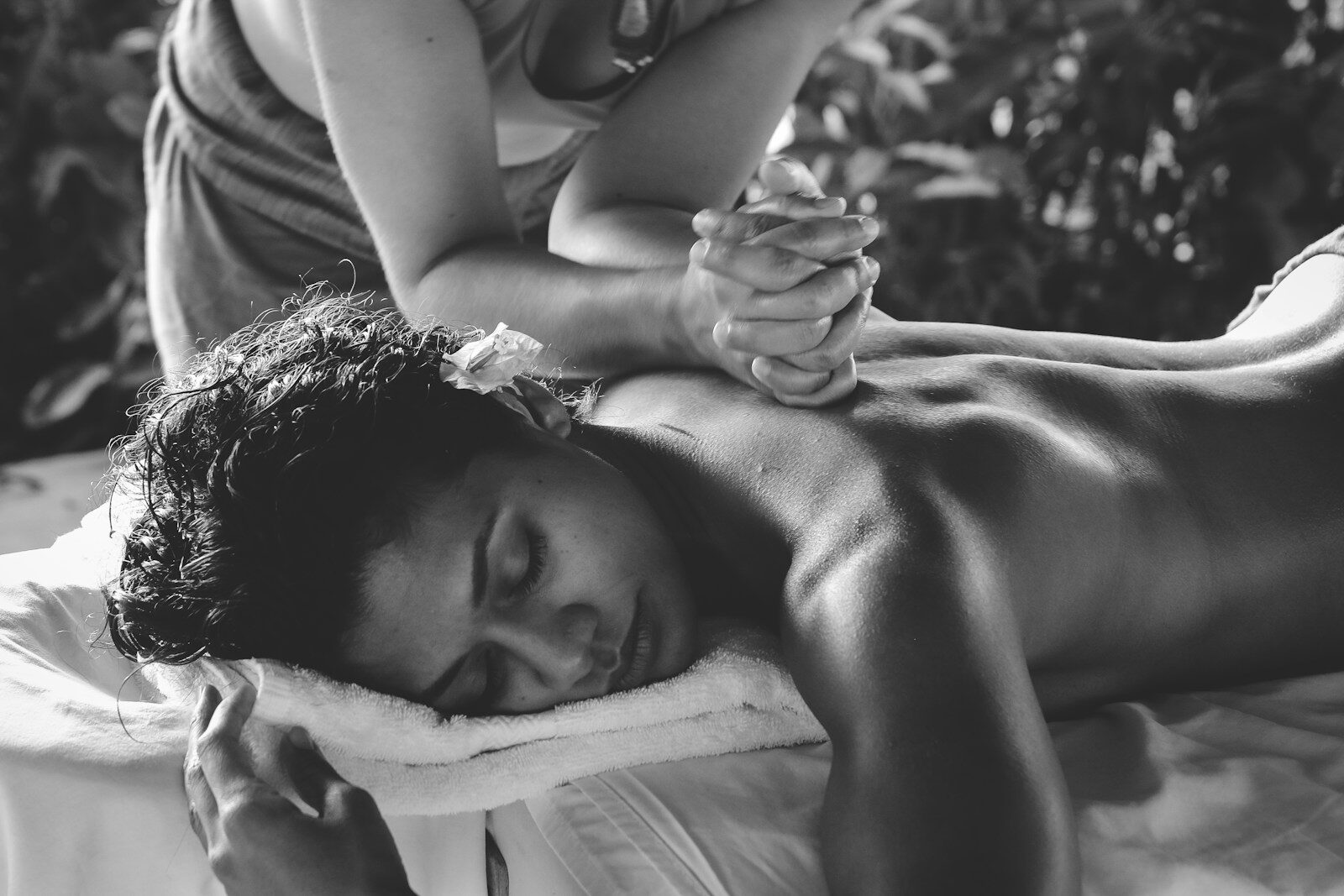A person receiving a back massage from a therapist in a black and white